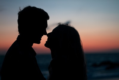 日落时，男人和女人在海滩上亲吻的剪影